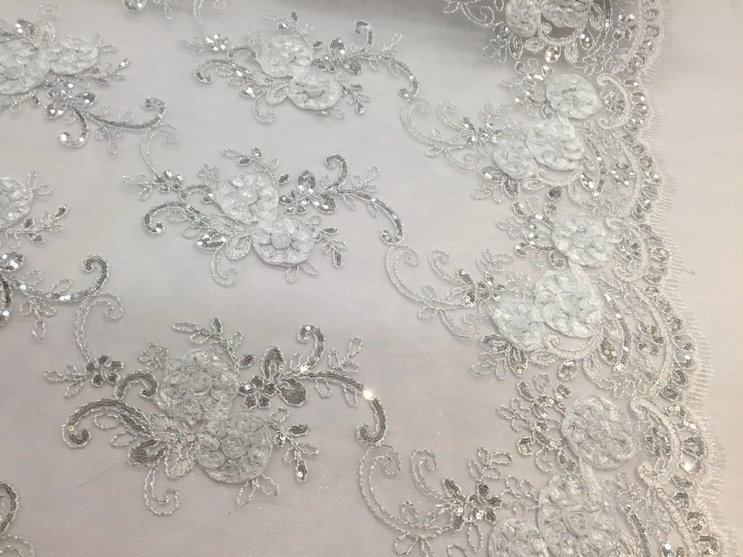 White  3d flowers embroider with sequins on a mesh lace fabric. Sold by the yard.