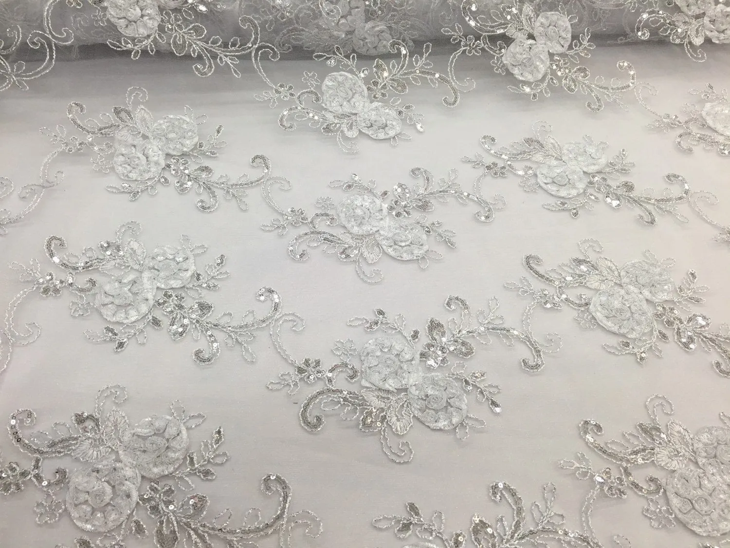 White  3d flowers embroider with sequins on a mesh lace fabric. Sold by the yard.