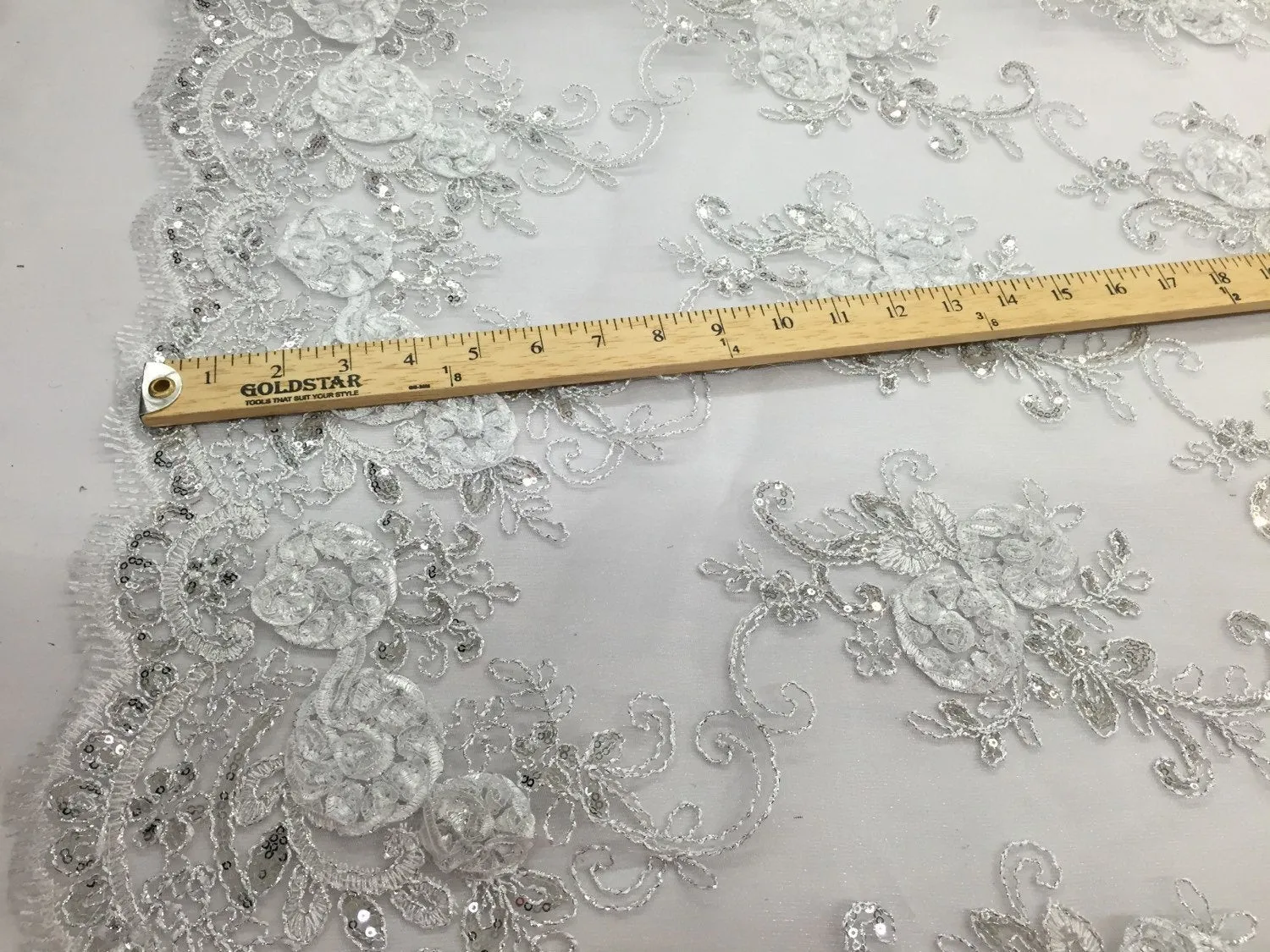 White  3d flowers embroider with sequins on a mesh lace fabric. Sold by the yard.