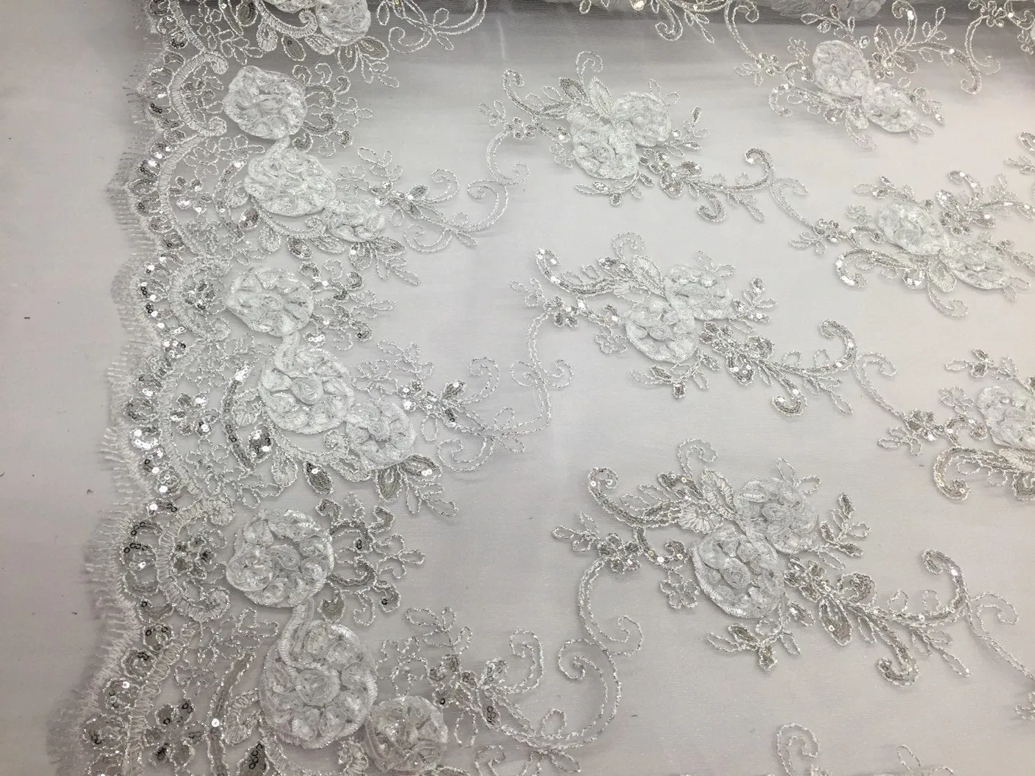 White  3d flowers embroider with sequins on a mesh lace fabric. Sold by the yard.